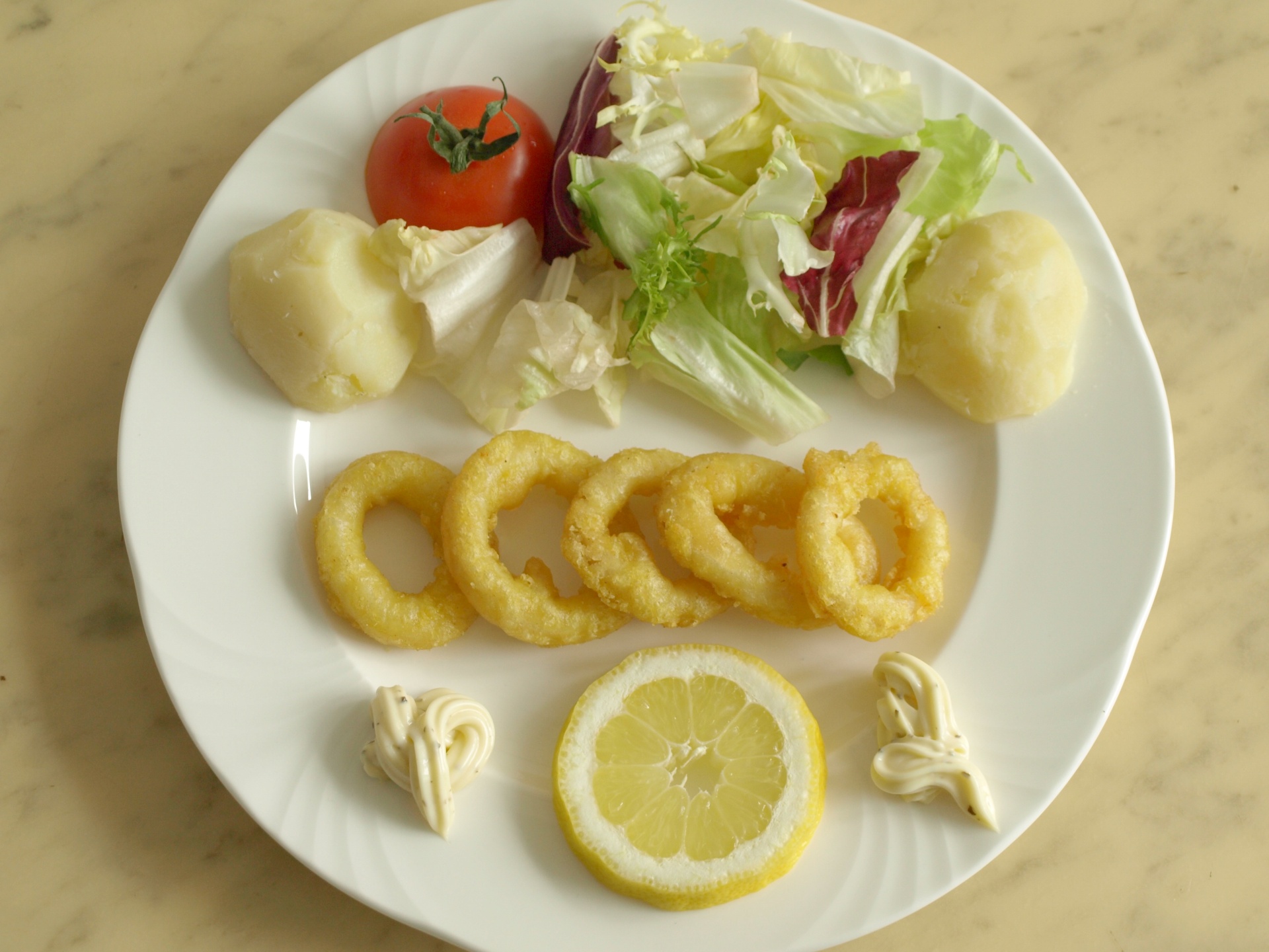 Panierte Tintenfischringe mit Kartoffeln und
              Salat