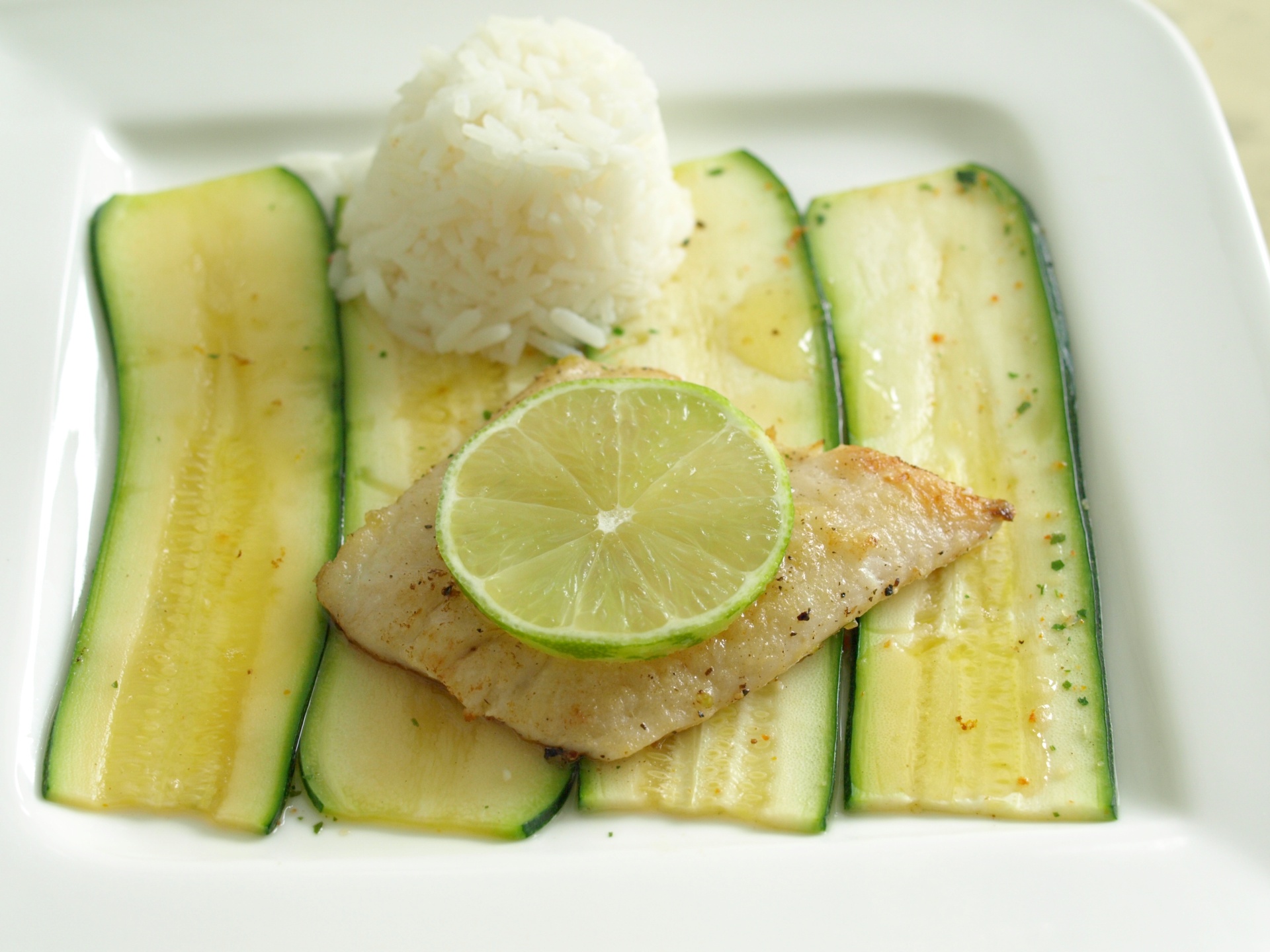 Seehechtfilets mit Limettenbutter auf
              Zucchini