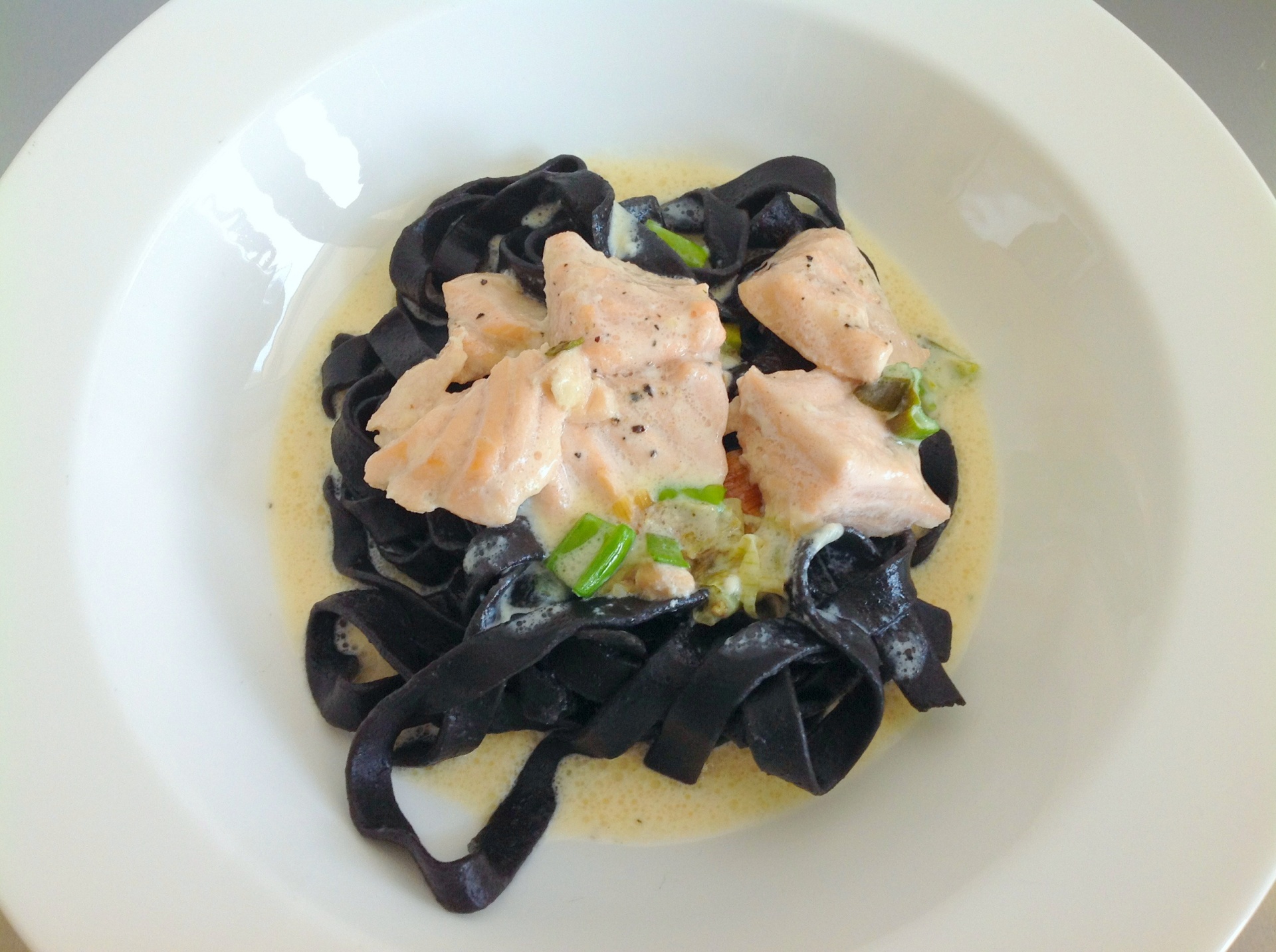 Schwarze Tagliatelle mit weier Sauce und
              gebratenem Lachs