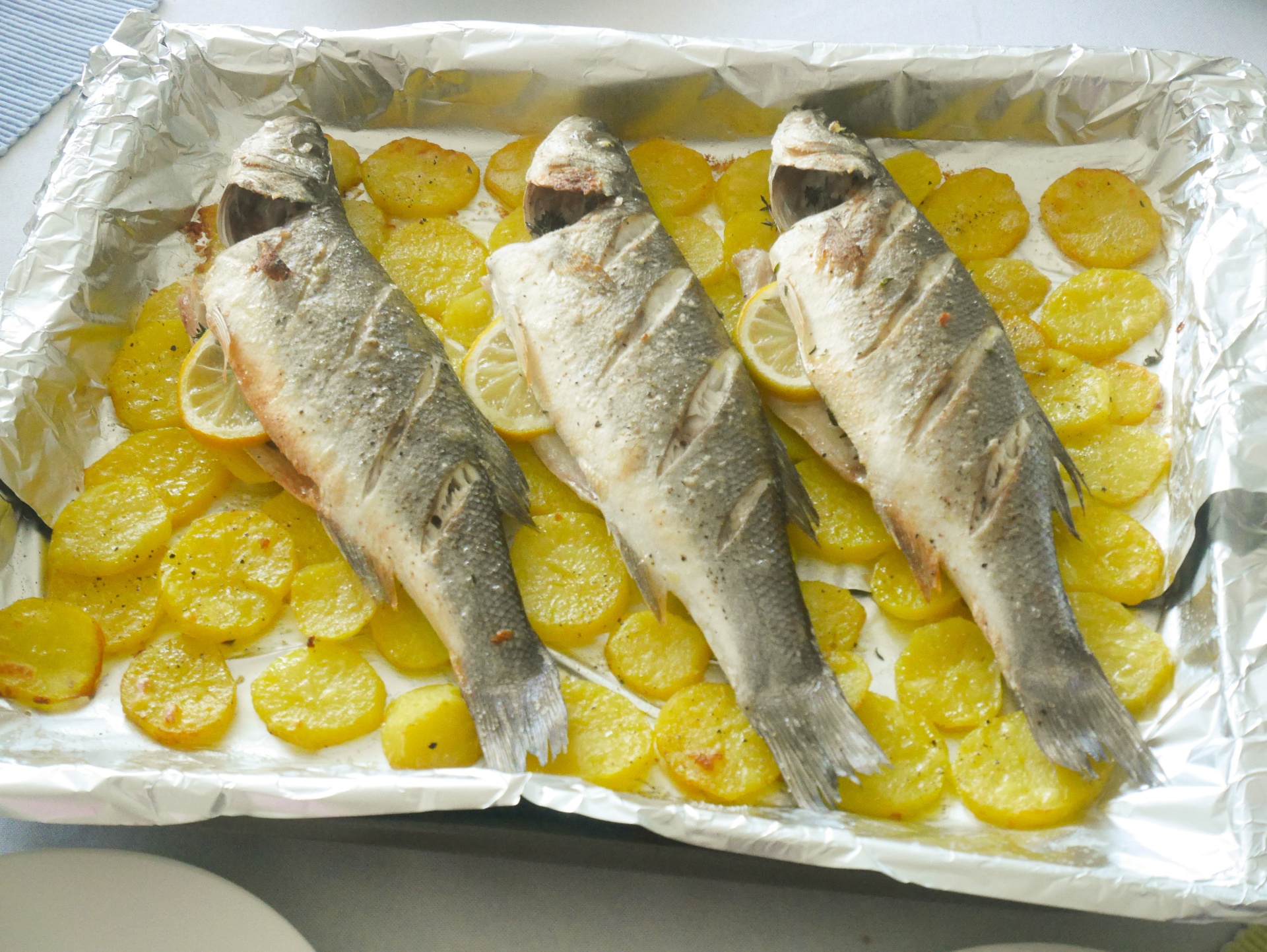 Wolfsbarsch im Ofen gebacken, auf
              Kartoffelscheiben